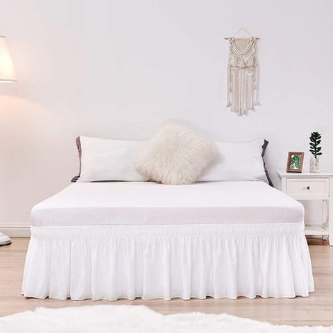 Elastic band wrap around white bed skirt without surface couvre lit.
